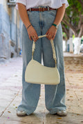 Sac Nour en cuir off white, tenu à la main avec tenue décontractée