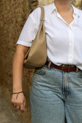 Sac Naomi cappuccino porté à la main – ambiance lifestyle, mur en fond